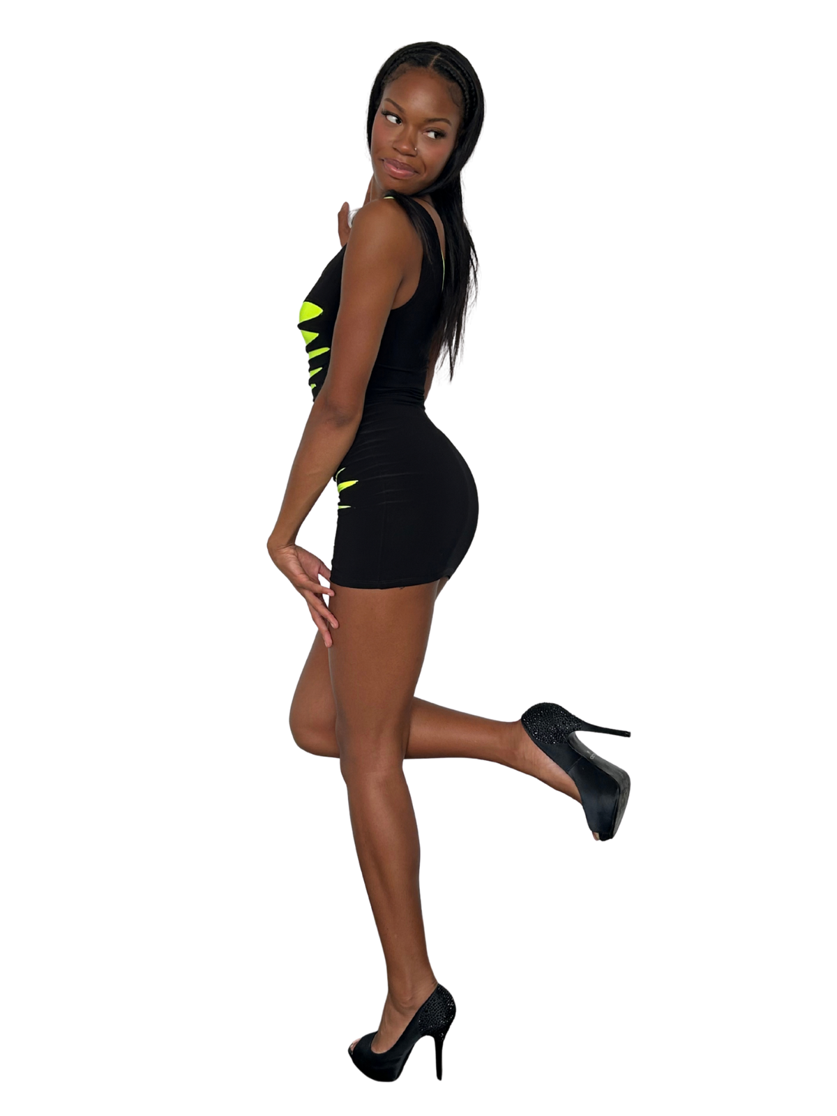 A woman posing in a black bodycon mini dress with bright neon yellow-green geometric accents on the bodice and hips, paired with black high heels, set against a plain white background.
